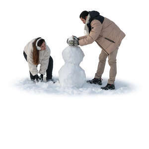 man and woman building a snowman in winter