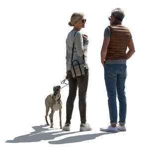 backlit man and woman with a dog standing and talking