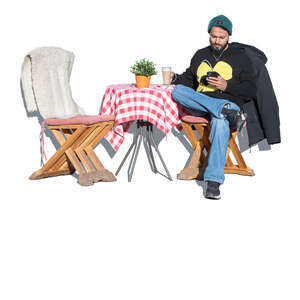 man sitting in an outdoor cafe on a sunny winter day