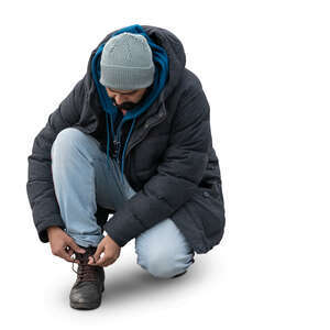 man squatting and tying his boot laces