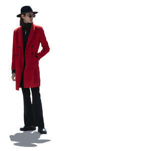 backlit man wearing a red coat and a black hat standing