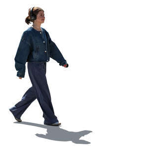 backlit young woman with headphones walking