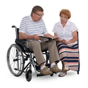 man in a wheelchair looking at a book together with his wife