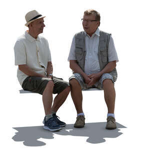 two backlit older men sitting and talking