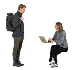 woman sitting and talking to a man with a backpack standing