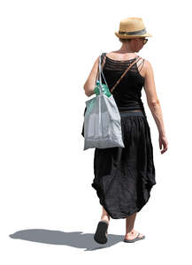 woman in a black summer outfit and wearing a hat walking