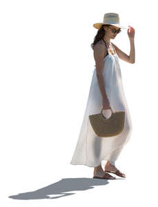 backlit woman in a long white beach dress walking