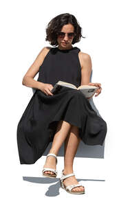 woman in a black dress sitting and reading a book