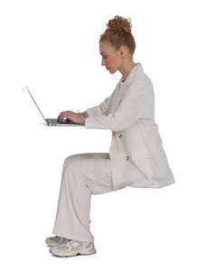 woman in a white suit sitting behind the desk and working with laptop