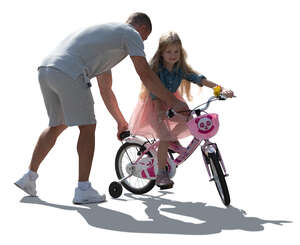 backlit man helping her daughter to ride a bike