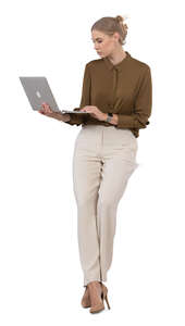 woman leaning against the desk and looking at her laptop