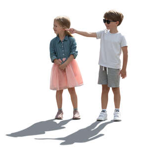 two backlit children standing and pointing at smth