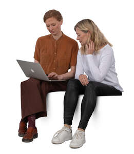 two women sitting side by side and looking at a laptop