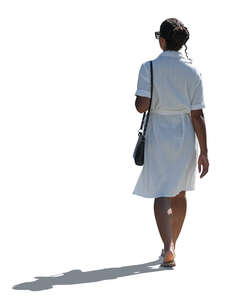 backlit woman in a white dress walking