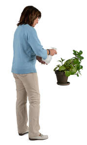 senior woman spraying houseplants with water