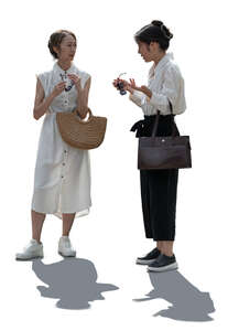 two backlit asian women standing and talking