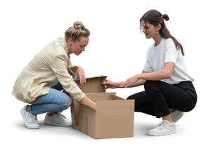 two women squatting and opening a carton box