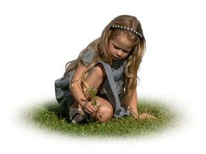 little girl sitting on the grass and picking flowers