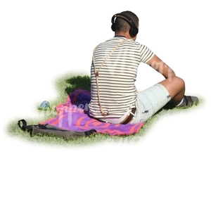 man with headphones sitting in a park on a blanket