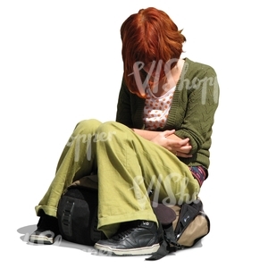 young woman with red hair and green clothes sitting on her backpack