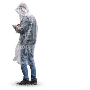 man in a raincoat standing and looking at his smartphone