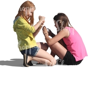 two girls sitting on the ground and playing