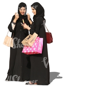 two young arab women in abayas standing and smiling