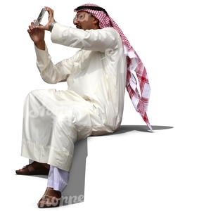 arab man in a thobe sitting and taking a picture