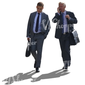 two backlit businessmen walking side by side