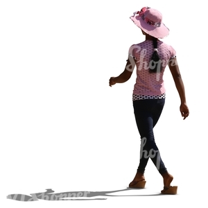 backlit black woman wearing a pink hat walking