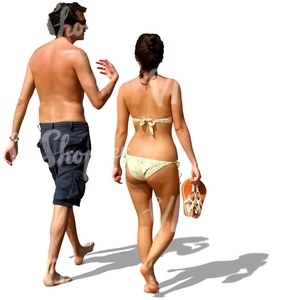 man and woman walking barefoot on the beach and talking