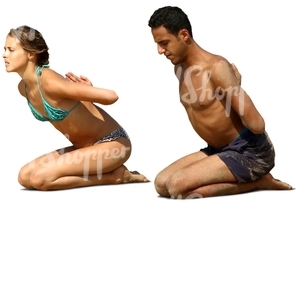 man and woman doing a yoga exercise on the beach