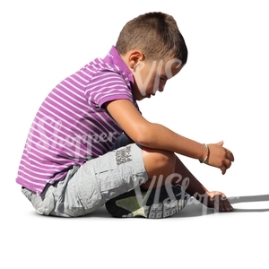 small boy sitting on the ground and playing