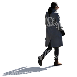 backlit woman in a grey overcoat walking