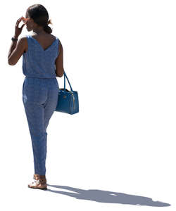 backlit woman in a blue jumpsuit standing