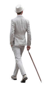 man in a white suit wearing a hat and holding a walking stick walking