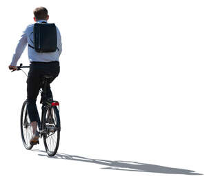 backlit office worker with a backpack riding a bike
