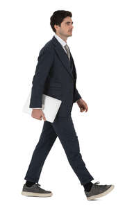 young businessman with a laptop walking