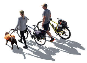 backlit man and a woman with bikes and a dog hiking