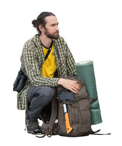 male hiker with backpacks squatting