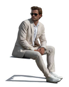 man in a white suit sitting outside in the sun