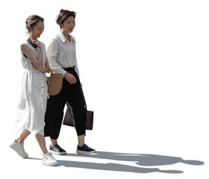 two backlit asian women walking