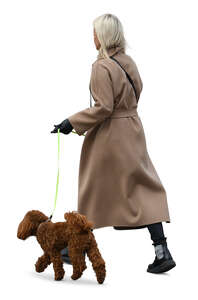 woman in a brown overcoat walking a dog