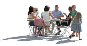 backlit scene of many adults and kids sitting around the table