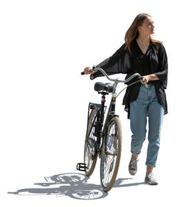 backlit young woman with a bike walking