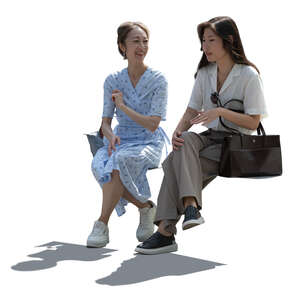 two backlit asian women sitting and talking