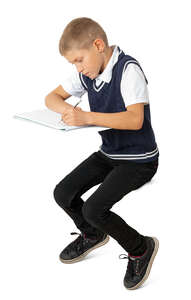 school boy sitting in class and writing