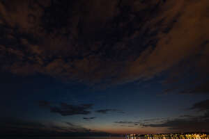 night sky with few clouds and lights