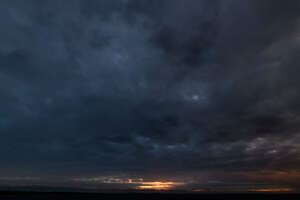 dark cloudy sky with sun setting