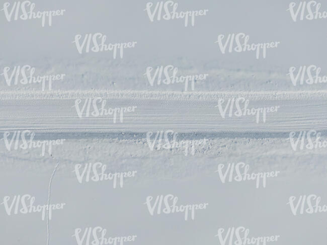 snow covered road between snow fields seen from above